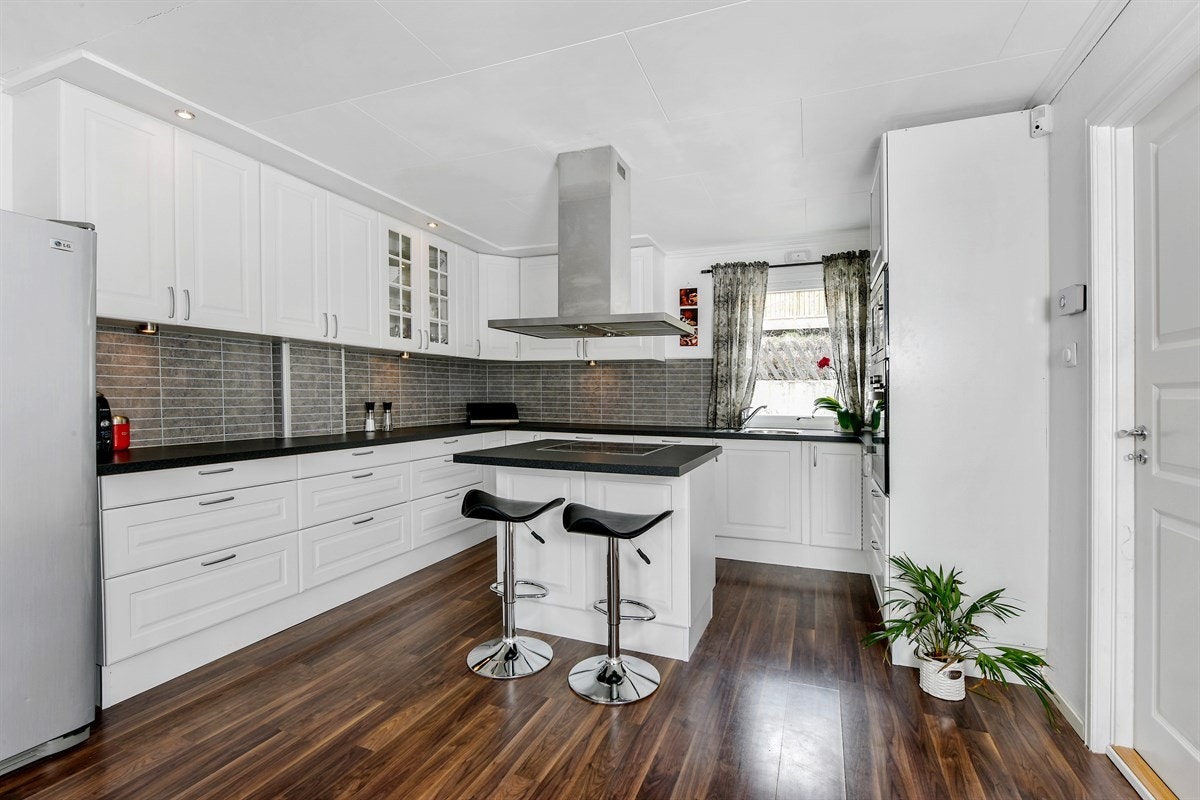 Kjøkkenet er lyst og meget elegant med god benke- og lagringsplass, samt sentrert kjøkkenøy mot stuen med nedfelt induksjonstopp, overhengende ventilator,og spiseplass. Galleribilde