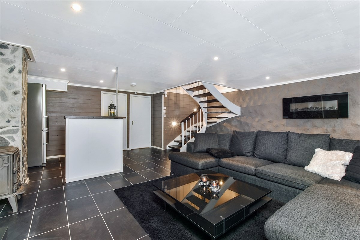 Kjellerstuen fremstår som hentet ute av et boligmagasin, og er stilfullt oppusset med antrasittgrå fliser på gulv, samt grove, gråpussede vegger. Galleribilde