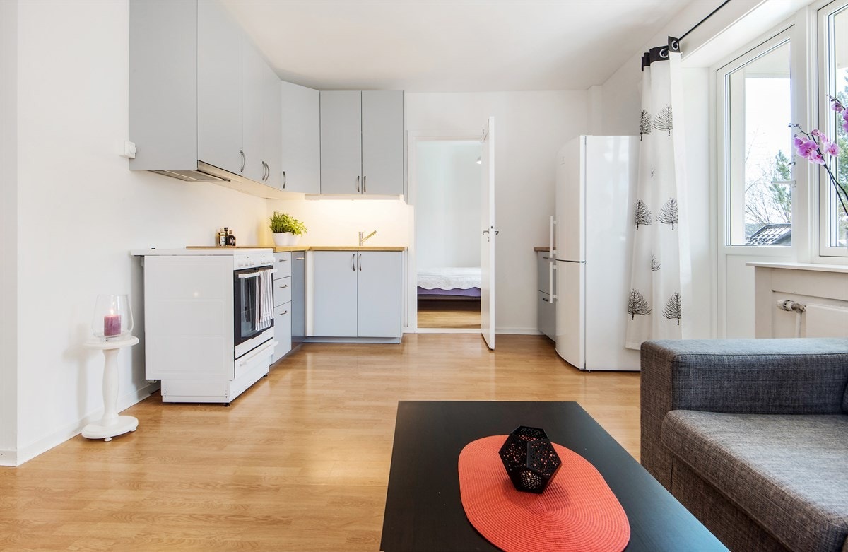 Kjøkkenet fra 2014 er moderne og effektivt med lysegrå glatte fronter, benkebelysning og heltre benkeplate med enkel vaskekum. Galleribilde