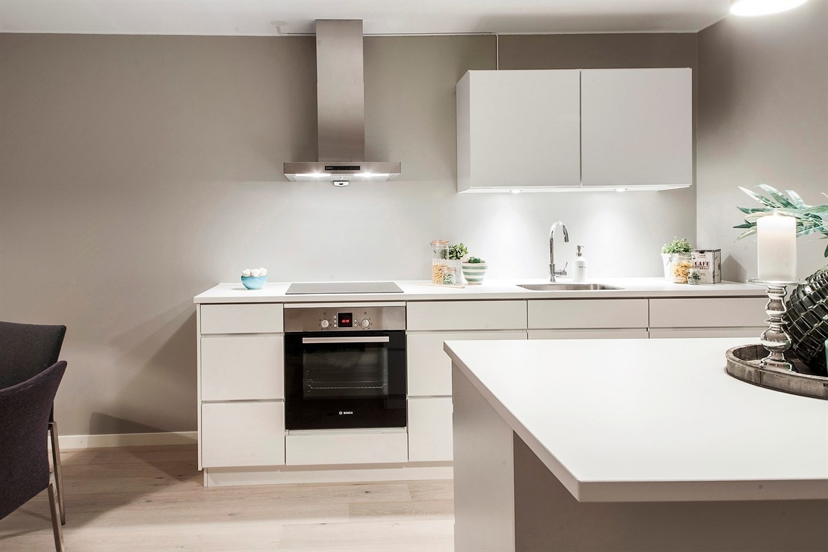 Kjøkkenet fra KVIK er nytt og fremstår som stilrent. Alle hvitevarene er fra Bosch, og integrert i en moderne innredning med glatte fronter. Bardisk mot stuen med sitteplasser. Galleribilde