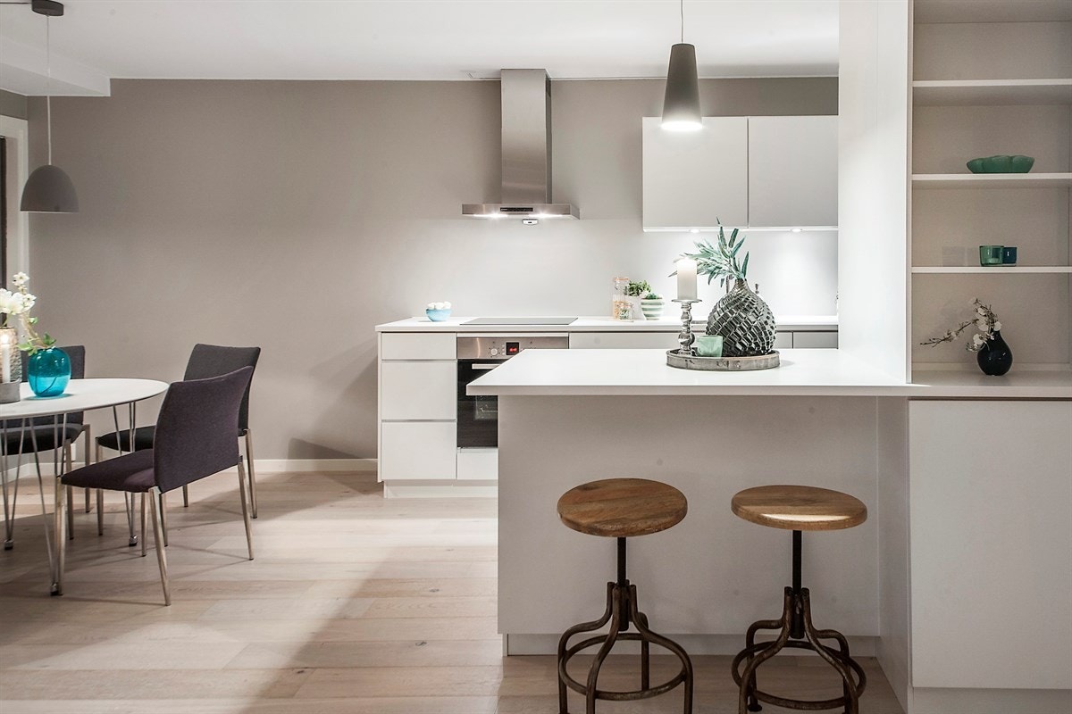 Kjøkkenet fra KVIK er nytt og fremstår som stilrent. Alle hvitevarene er fra Bosch, og integrert i en moderne innredning med glatte fronter. Bardisk mot stuen med sitteplasser. Galleribilde