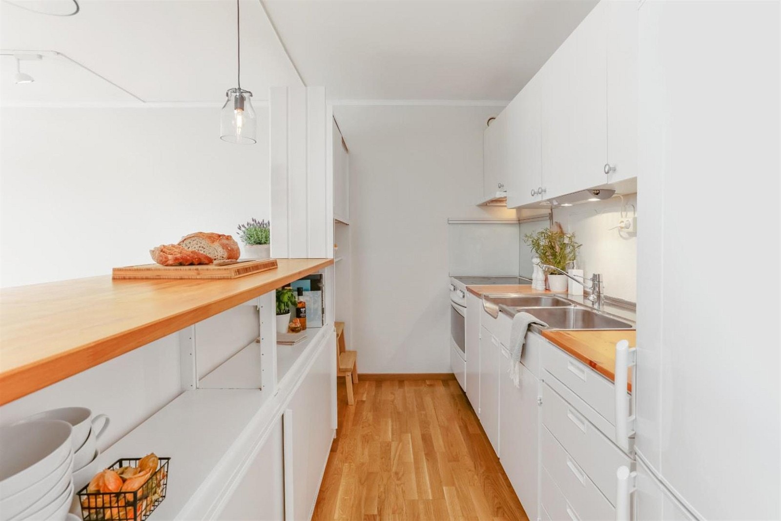 Kjøkkeninnredning med malte glatte fronter, benkeplate i lakkert heltre, belysning under overskap, stål benkebeslag og skyllekum med ettgreps blandebatteri Galleribilde