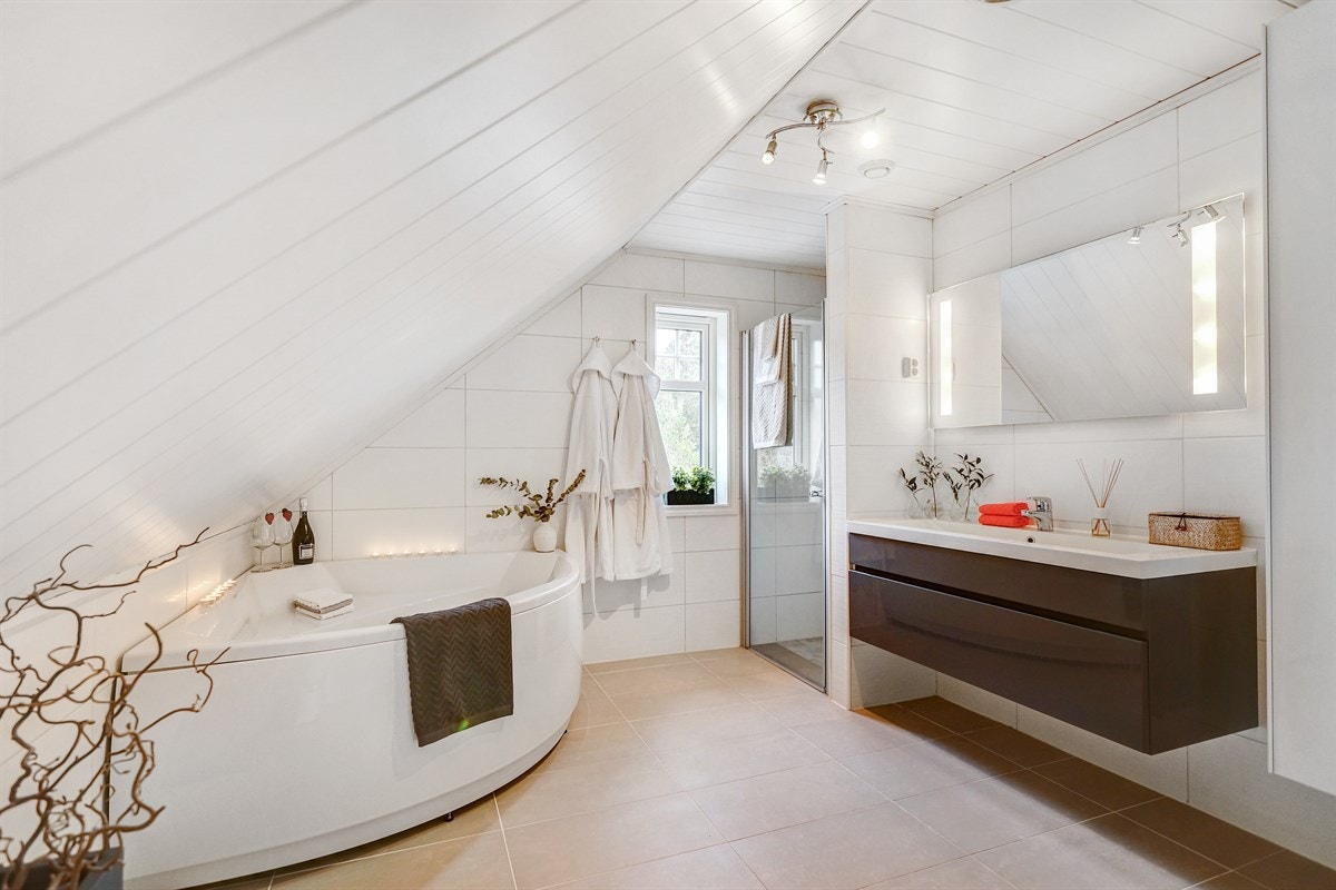 Nydelig bad med hjørnebadekar, separat dusjhjørne og mørk grå høyglans baderomsinnredning. Galleribilde