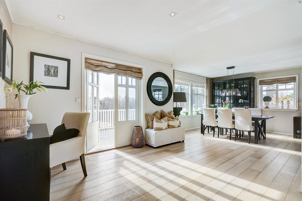 Dobbel dør ut til stor terrasse som går rundt til hage på framsiden av boligen. Galleribilde