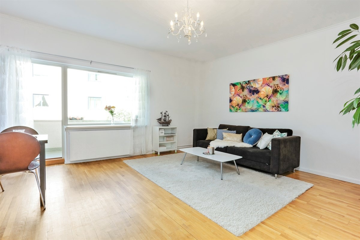 Stuen vender ut mot balkongen og skjermede fellesarealer. Galleribilde