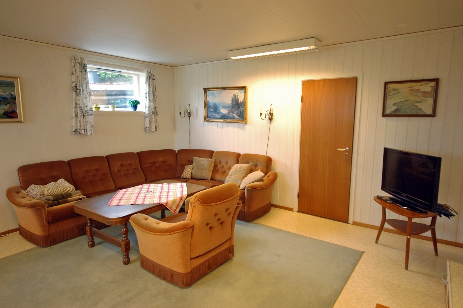 Stova med dør inn til soverom og lita trapp opp til kjøkkenent til høgre. Galleribilde