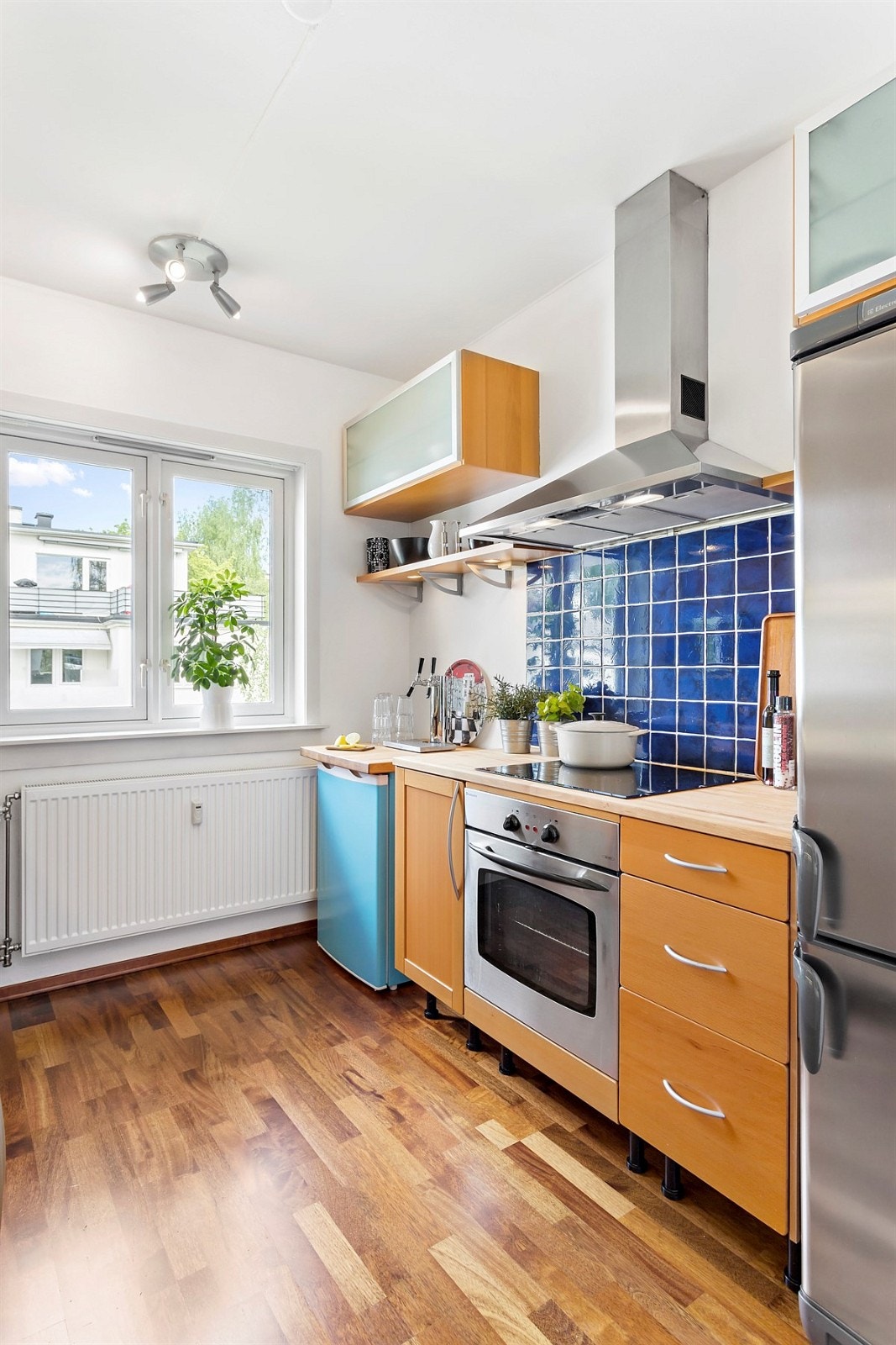 På kjøkkenet er overflatene lyse, fliser over komfyr, parkett på gulv. Galleribilde
