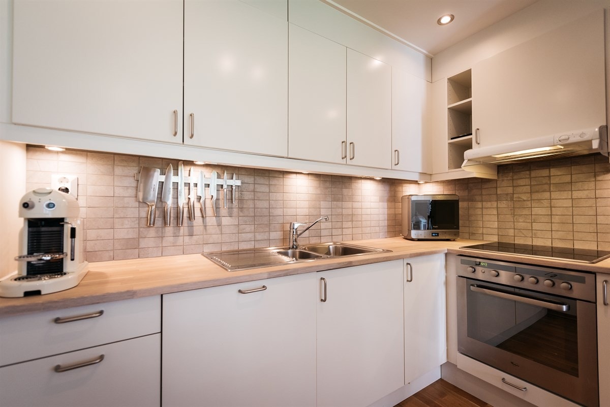 Kjøkkenet har ny benkeplate, stålkum og fliser over benken. Integrert koketopp, komfyr og oppvaskmaskin Galleribilde