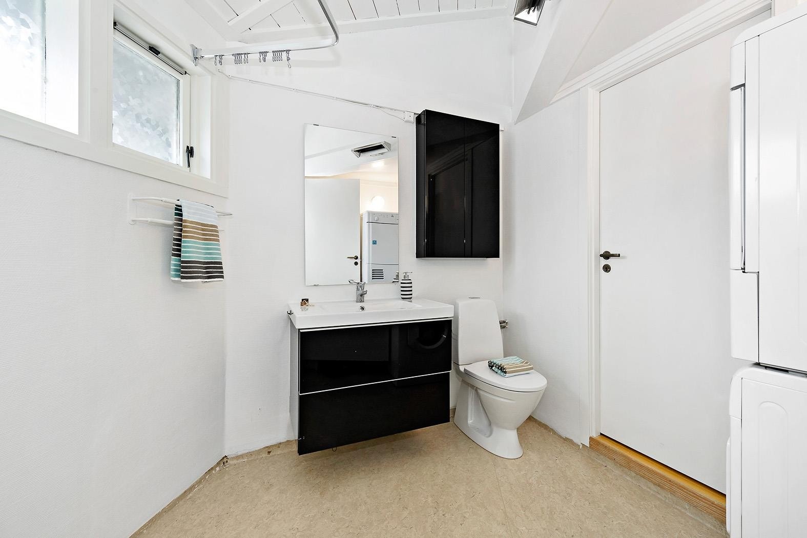 Badet holder en generell eldre standard. Nymalte overflater og eldre belegg på gulv. Innredet med dusjhjørne, wc, servant, skap, speil og røropplegg for vaskemaskin og tørketrommel. Galleribilde