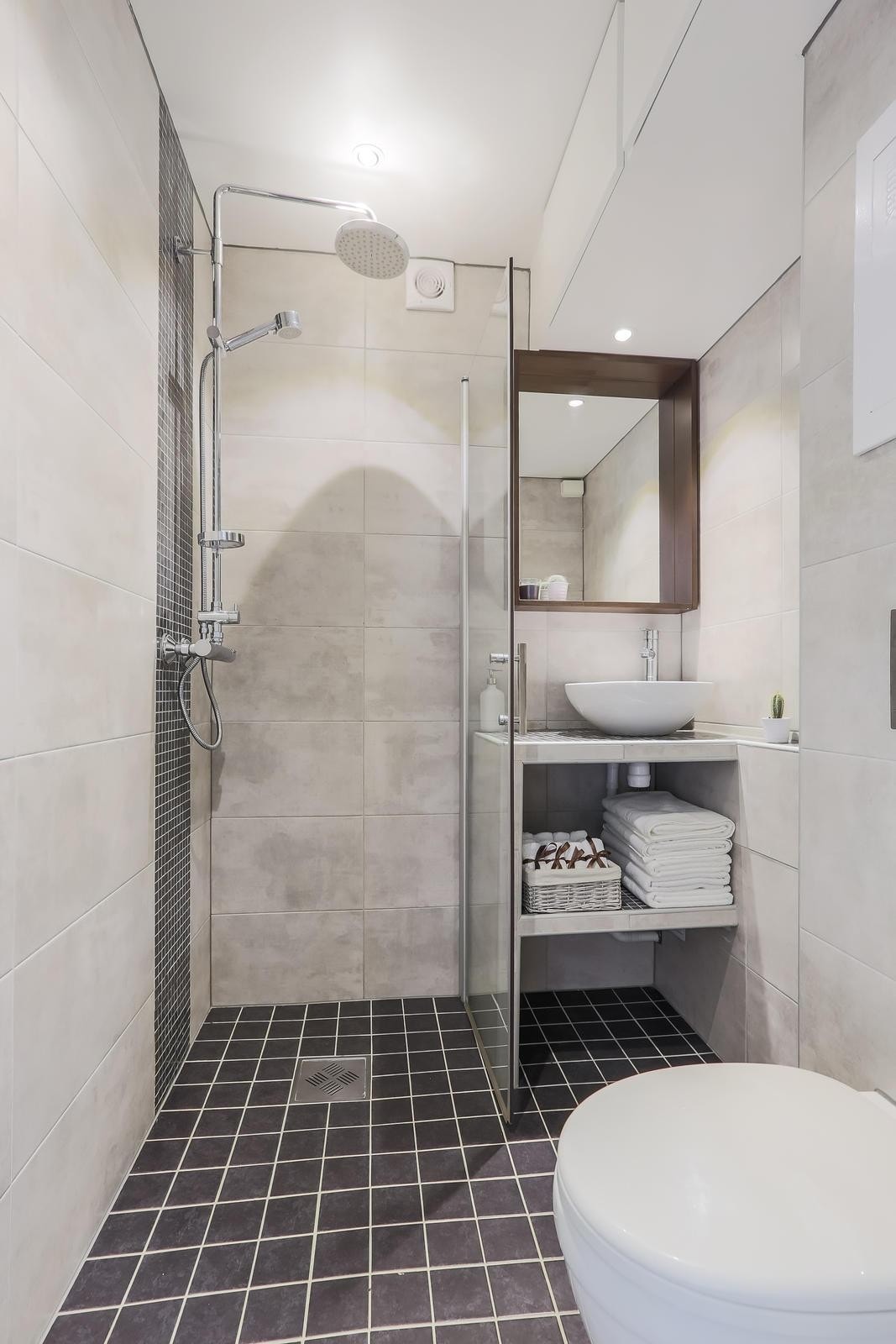 Badet innehar vegghengt toalett, dusjnisje og servant med hyller. Galleribilde