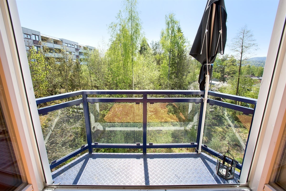 Leiligheten har utgang fra stuen til en liten balkong med glassrekkverk og en åpen, langtrekkende utsikt. Galleribilde