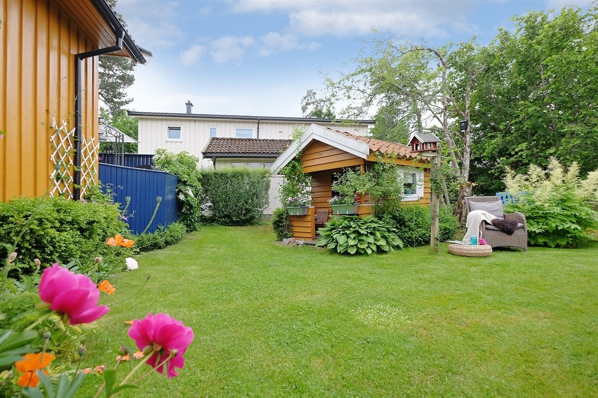 Pent opparbeidet eiendom med gressplen, beplantning og gruslagt gangvei til boligen Galleribilde