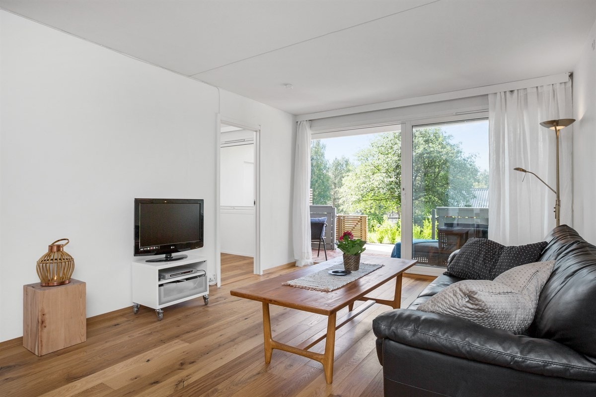 Lys og åpen stue med store vindusflater med skyvedør vendt mot nydelig uteplass. Galleribilde