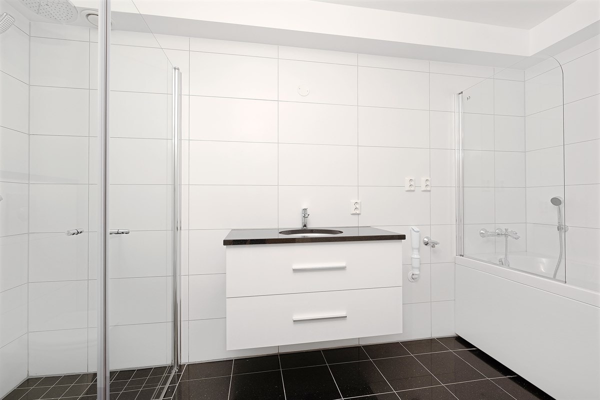 Badene i boligen er meget stilfulle, helfliset med varme i gulv ( benkeplate og gulvflis = Black Galaxy granitt) og innredet med servant, veggehengt toalett og dusjhjørne (bad/wc i første etasje har også badekar) Galleribilde