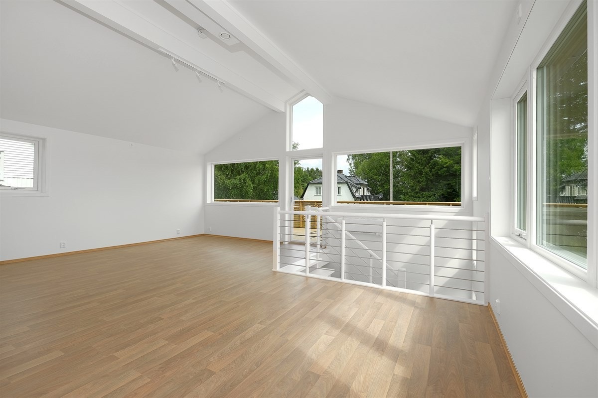 Romslig stue med god plass til sofagruppe. Store vindusflater og terrassedør gir rikelig med lys til rommet. Moderne gulv og lyse vegger skaper en god atmosfære. Stuen har en åpen løsning mot kjøkkenet og trapp ned til første etasje. Galleribilde