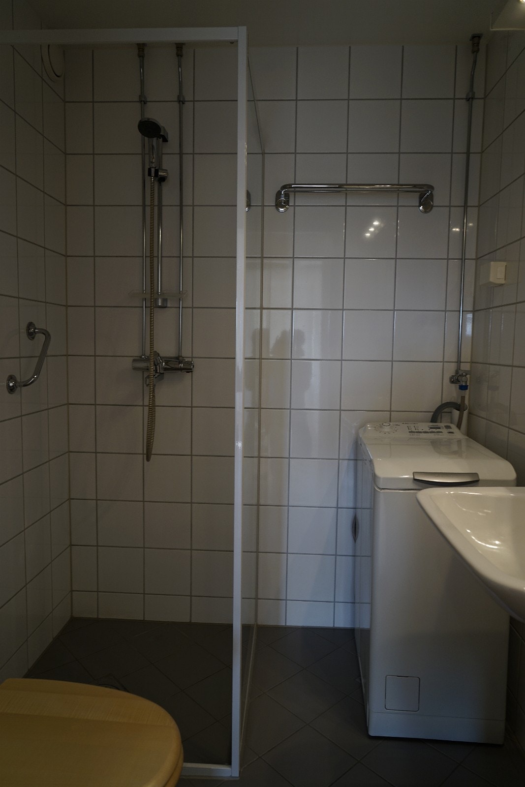 Flislagt bad med dusj, toalett og vaskemaskin Galleribilde