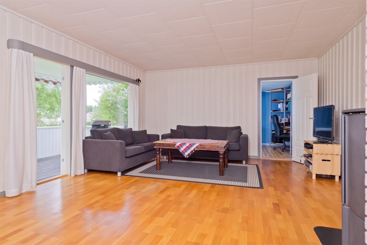 Stue med store vindusflater, god plass til sofa og her med adkomst til et av soverommene. Galleribilde