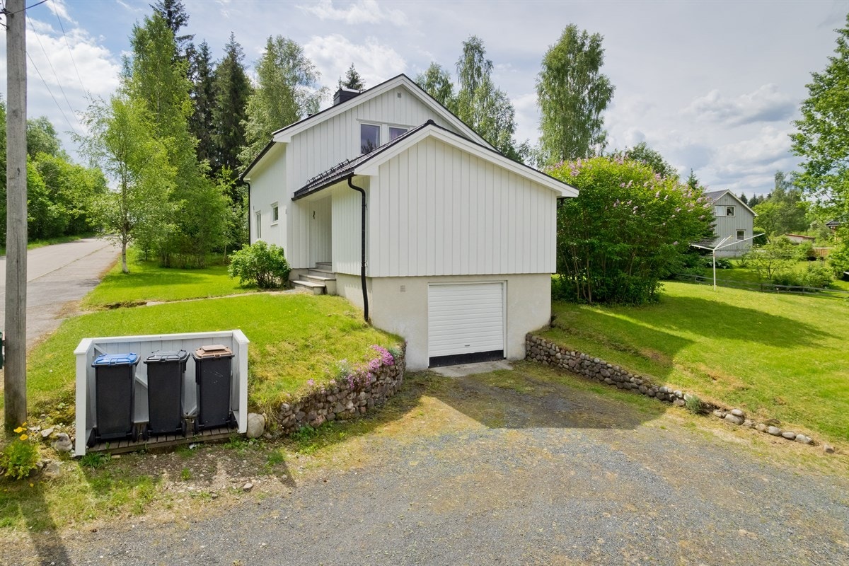 Gruset gårdsplass med flere biloppstillingsplasser og garasje i kjeller. Galleribilde