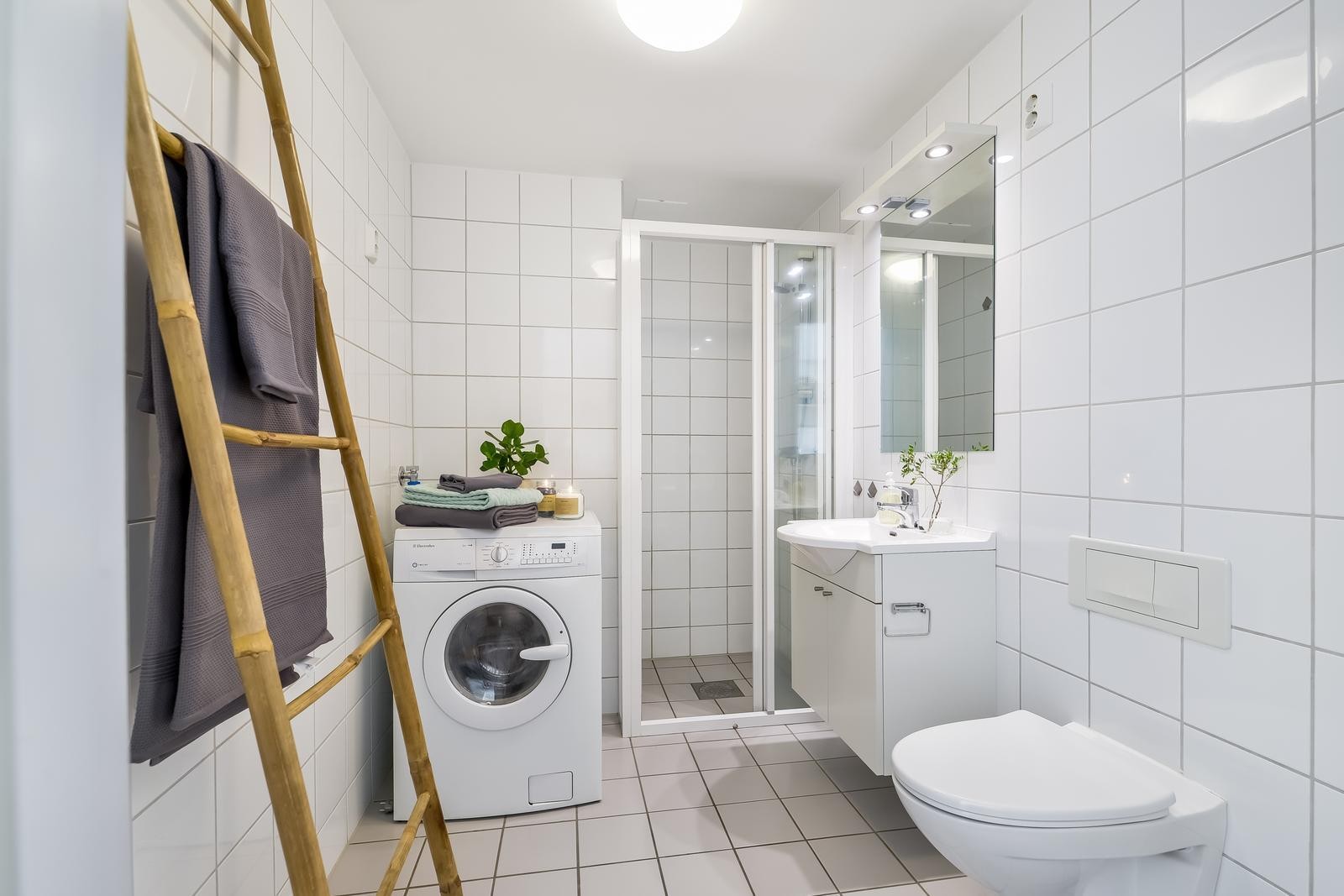 Leilighetens flislagte bad fremstår som fint og moderne. Veggmontert WC og opplegg for vaskemaskin. Galleribilde