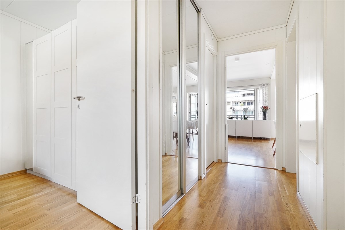 Entreen gir et lyst og hyggelig førsteinntrykk, og er i likhet med de øvrige rommene i leiligheten pent innredet med lysmalte vegger og eikeparkett på gulv. Rommet har skyvedørsgarderobe med speilfronter og en tilliggende lagringsbod. Galleribilde
