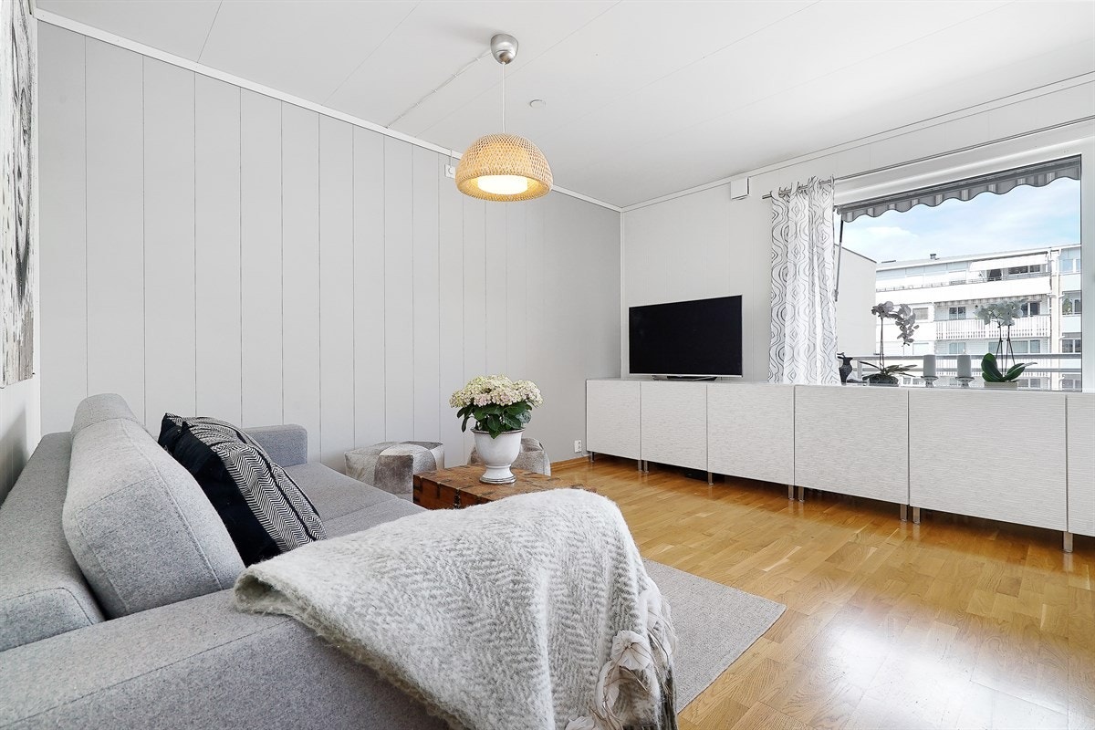 Stuen er lys og sjarmerende innredet med parkettgulv og panel på veggene, hvor en grå fondvegg gir en smakfull kontrast. For øvrig har stuen store vinduer som slipper inn godt med dagslys. Galleribilde