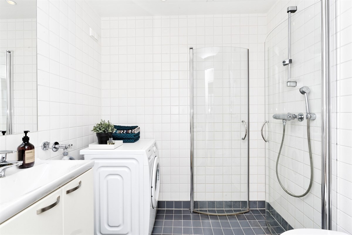 Pent pg praktisk bad med opplegg til vaskemaskin og dusjhjørne med innsvingbare skjermvegger i glass Galleribilde