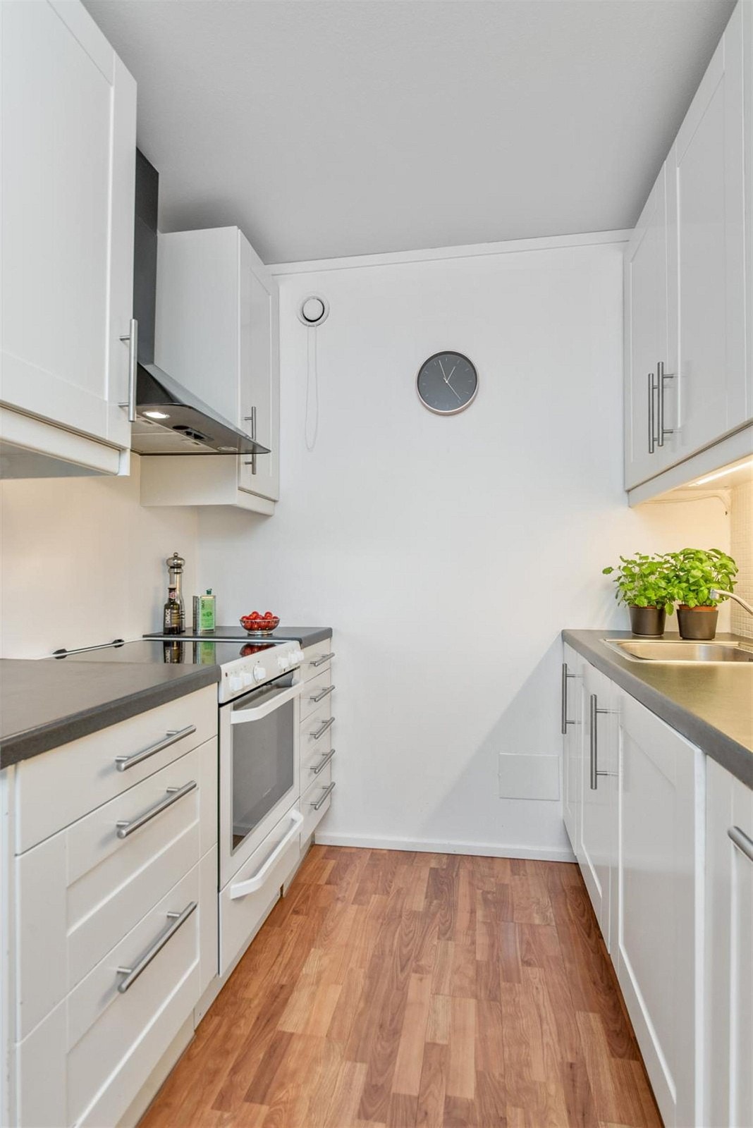 Kjøkkeninnredning med profilerte skapfronter. Laminat benkeplater med nedfelt rustfritt kum. Delvis integrerte hvitevarer. Galleribilde