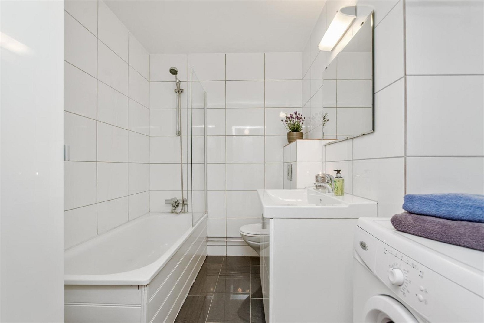 Pent flislagt bad med badekar, vaskemaskin og gulvvarme. Galleribilde