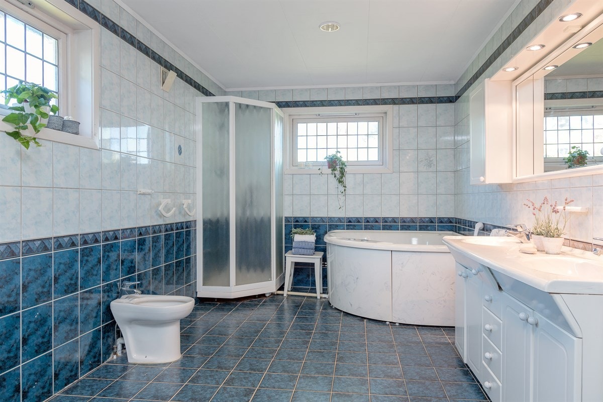 Boligen har totalt 3 romslige bad og et praktisk vaskerom i 1.etasje. Hovedbadet er av god størrelse og har flislagte overflater med varmekabler i gulv. Innredningen består av servantmøblement med under- og overskap, bidé, dusjkabinett og hjørnebadekar. Galleribilde