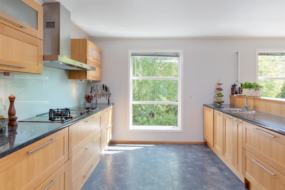 Innredningen har profilerte heltre eikefronter og eksklusiv granitt benkeplate med planlimt kum i rustfritt stål. Induksjonstopp, gassbluss, frityrkoker, grill, stekeovn, oppvaskmaskin og kaffemaskin er integrert i innredningen. Galleribilde