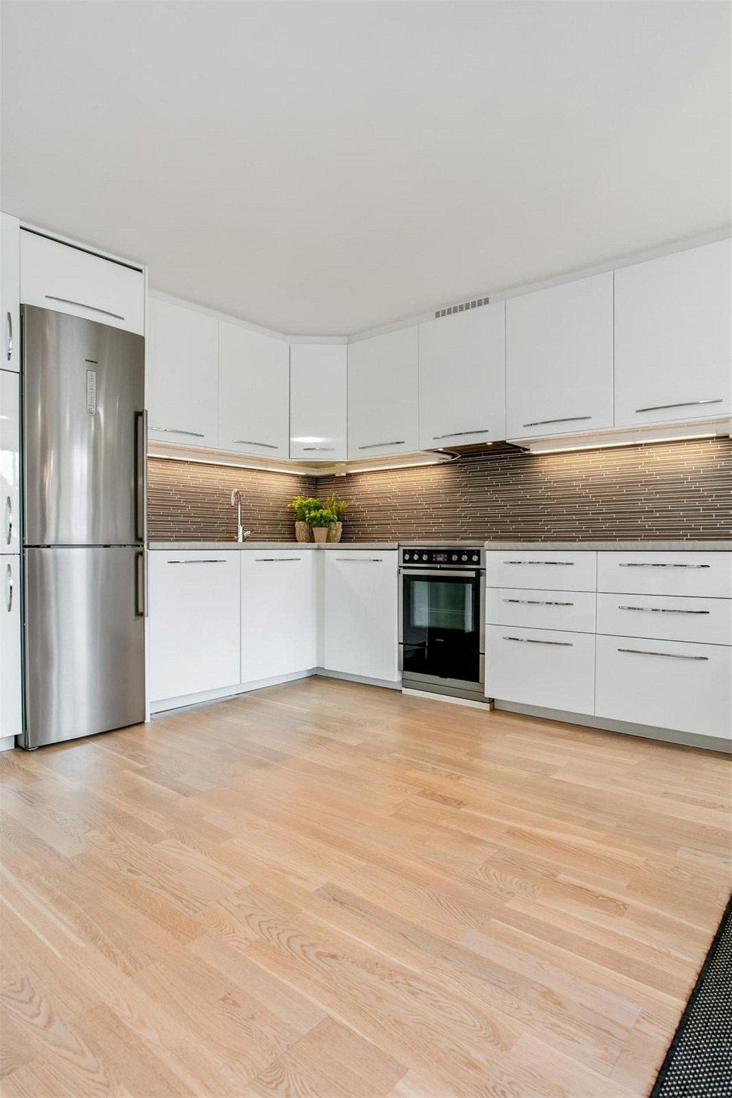 Kjøkkenet har integrerte hvitevarer og høyglans skapfronter. Galleribilde