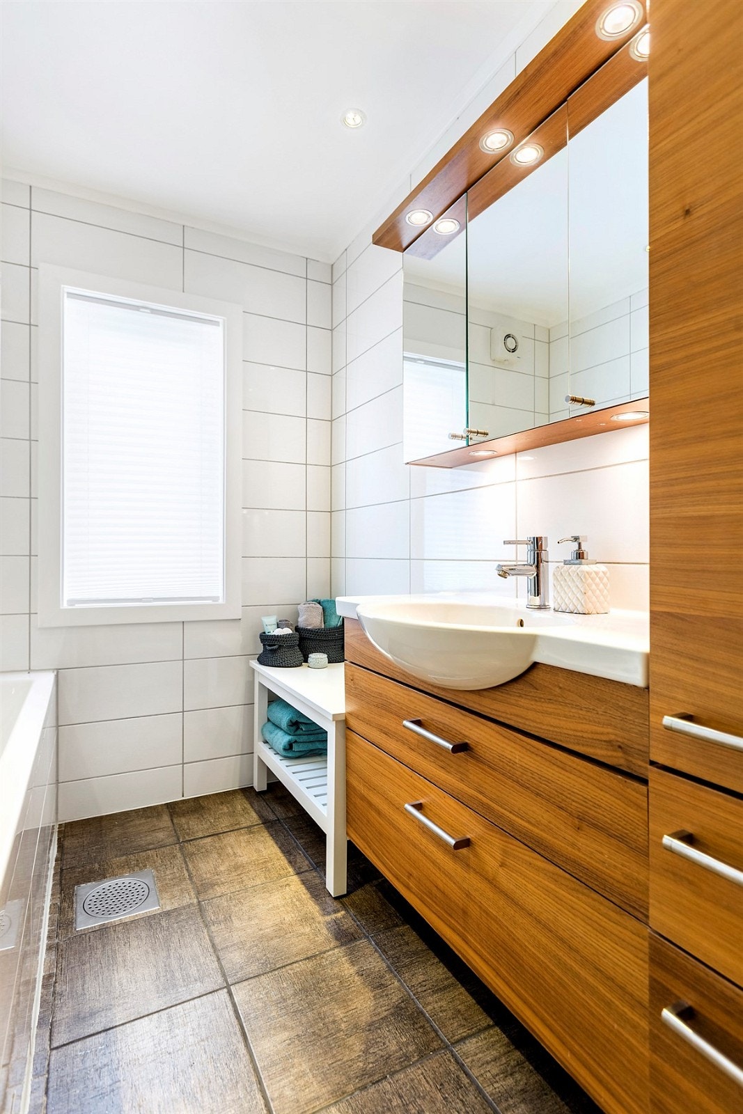 Videre har rommet gulvvarme, LED-downlights, elektrisk avtrekksvifte, speilskap med belysning og heldekkende servant på servantmøblement Galleribilde