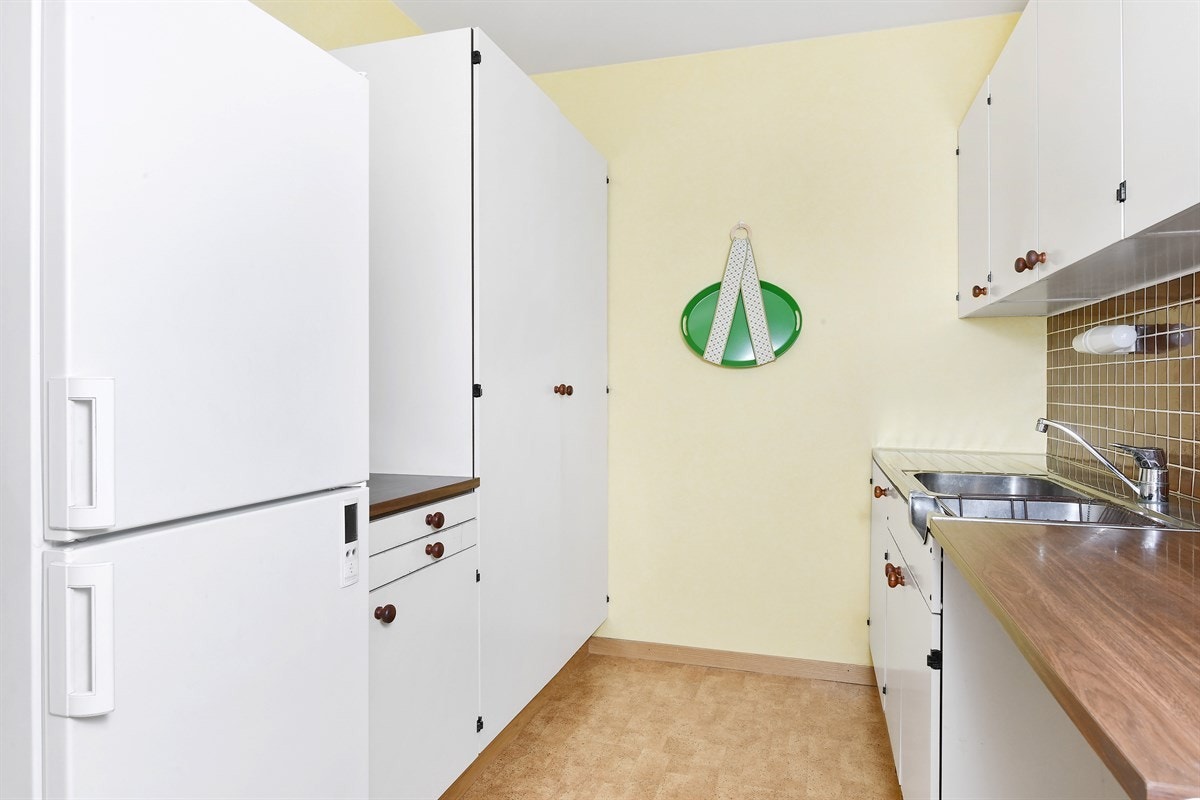 Videre er det benkebelysning og fliser over laminert benkeplate med dobbel vaskekum. Galleribilde