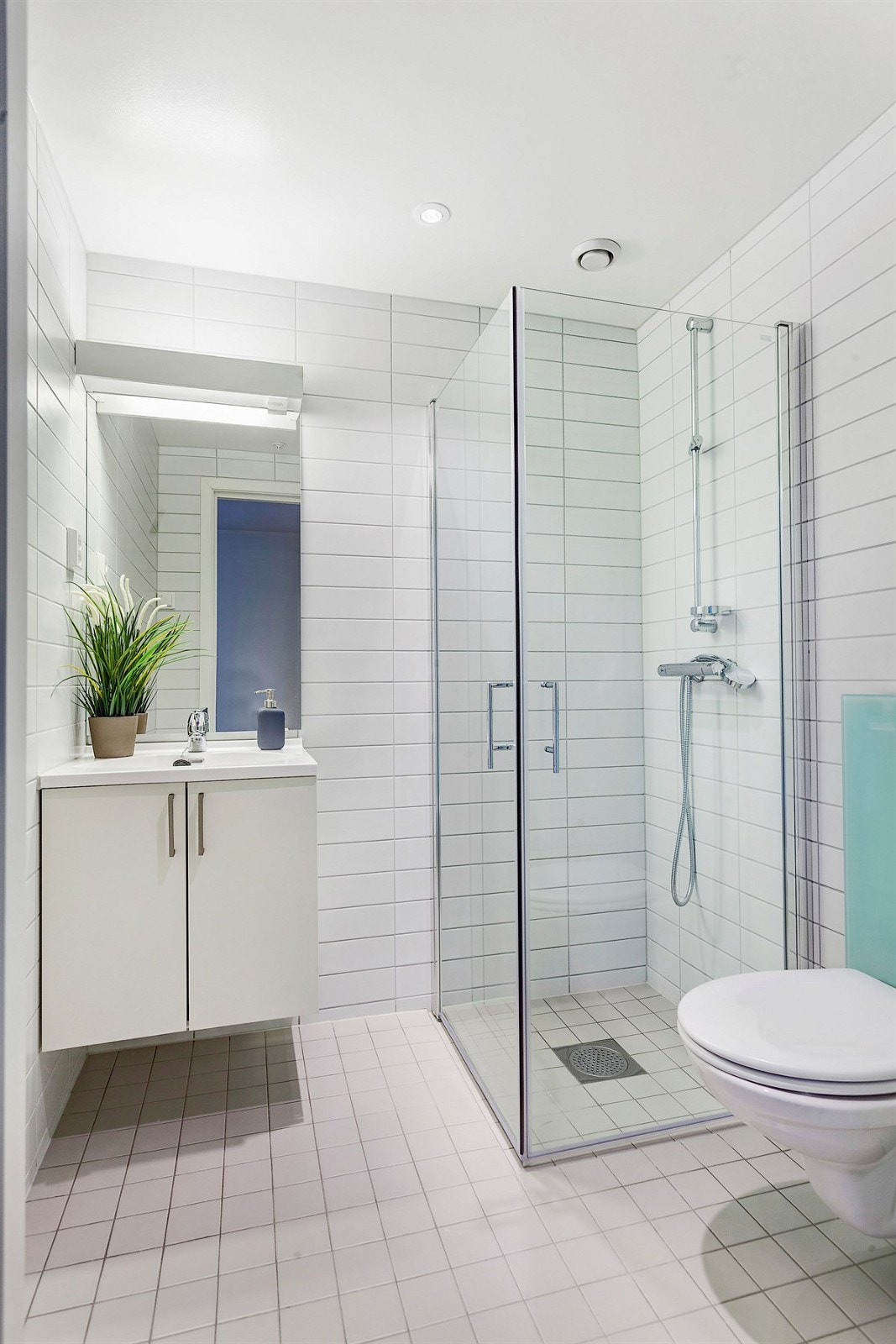 Bad 2 har vegghengt toalett, servant med ett-greps blandebatteri i krom, utenpåliggende speil, belysning, rette dusjvegger i herdet glass. Nedsenket dusjnisje. Galleribilde