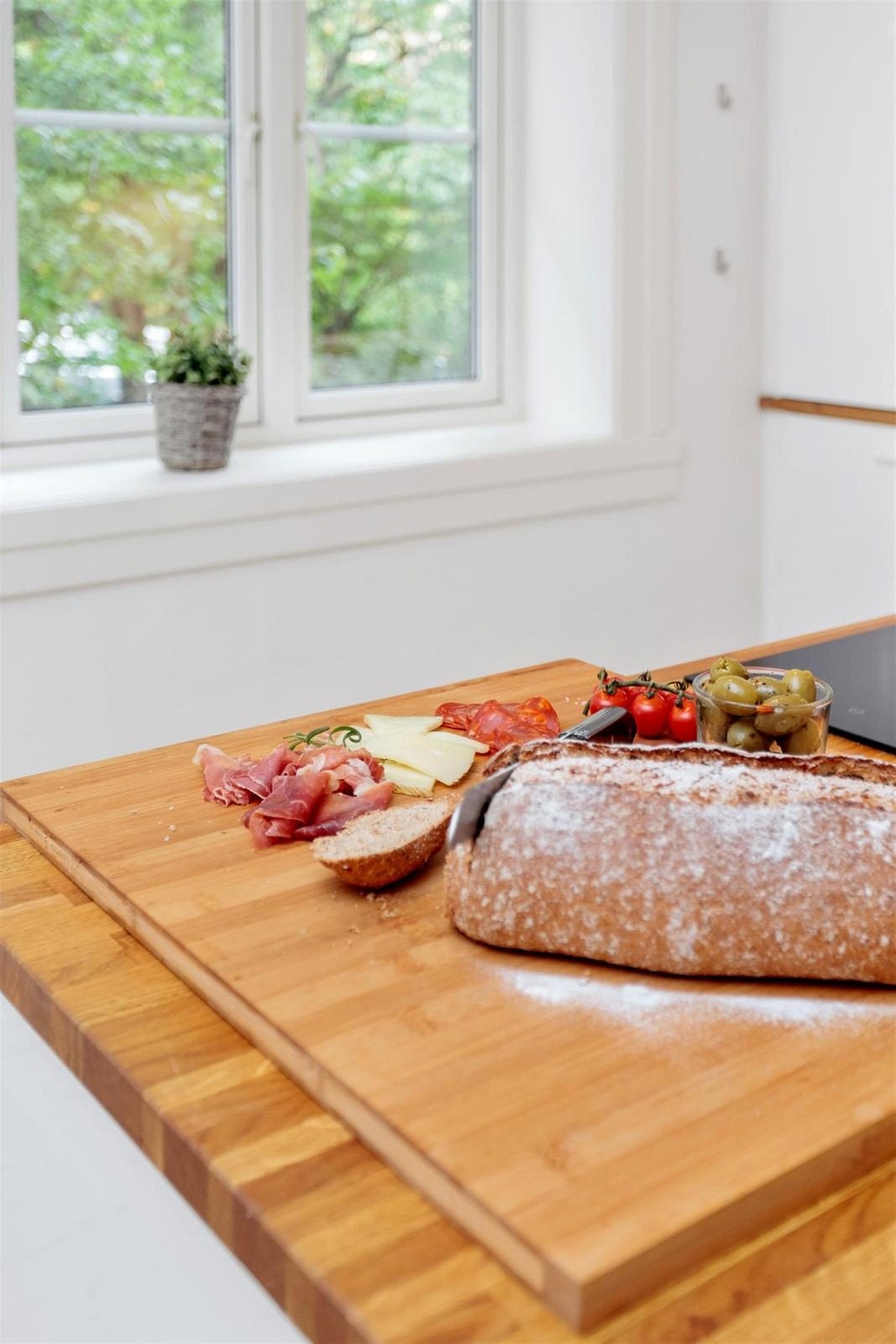 Vinduet på kjøkken vender ut mot stor, rolig og grønn bakgård. Galleribilde