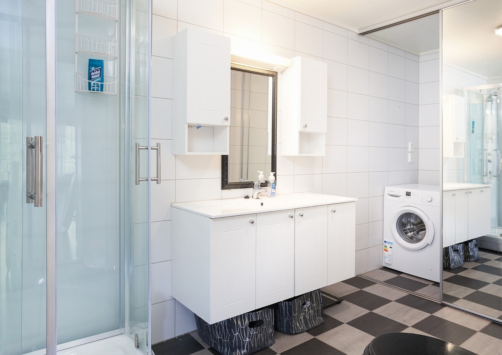 Badet har en praktisk nisje for vaskemaskin med skyvedører m/speil Galleribilde