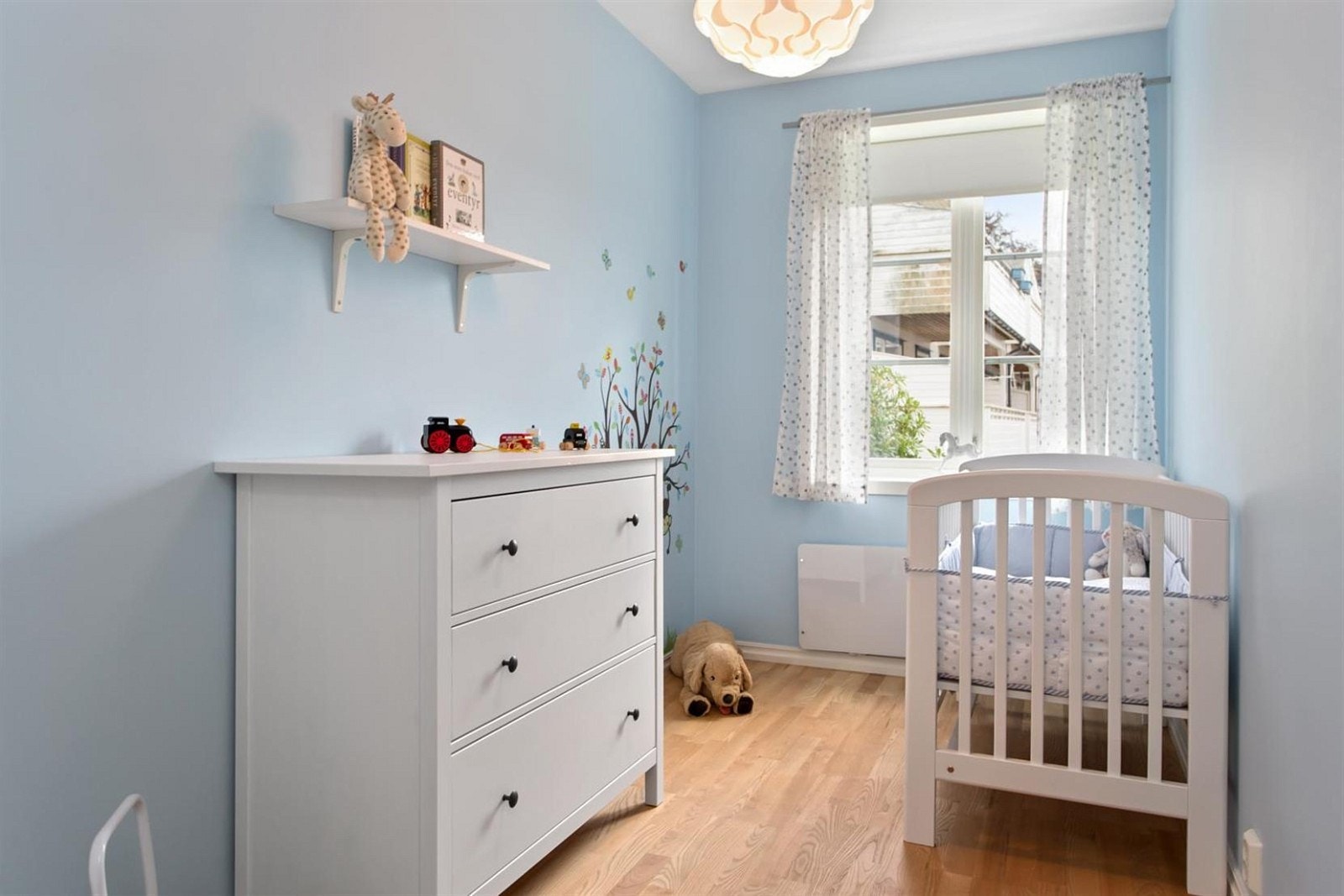 Trivelig og lyst barnerom malt i en lys blåfarge. Her er det plass til seng, kommode og garderobeskap Galleribilde