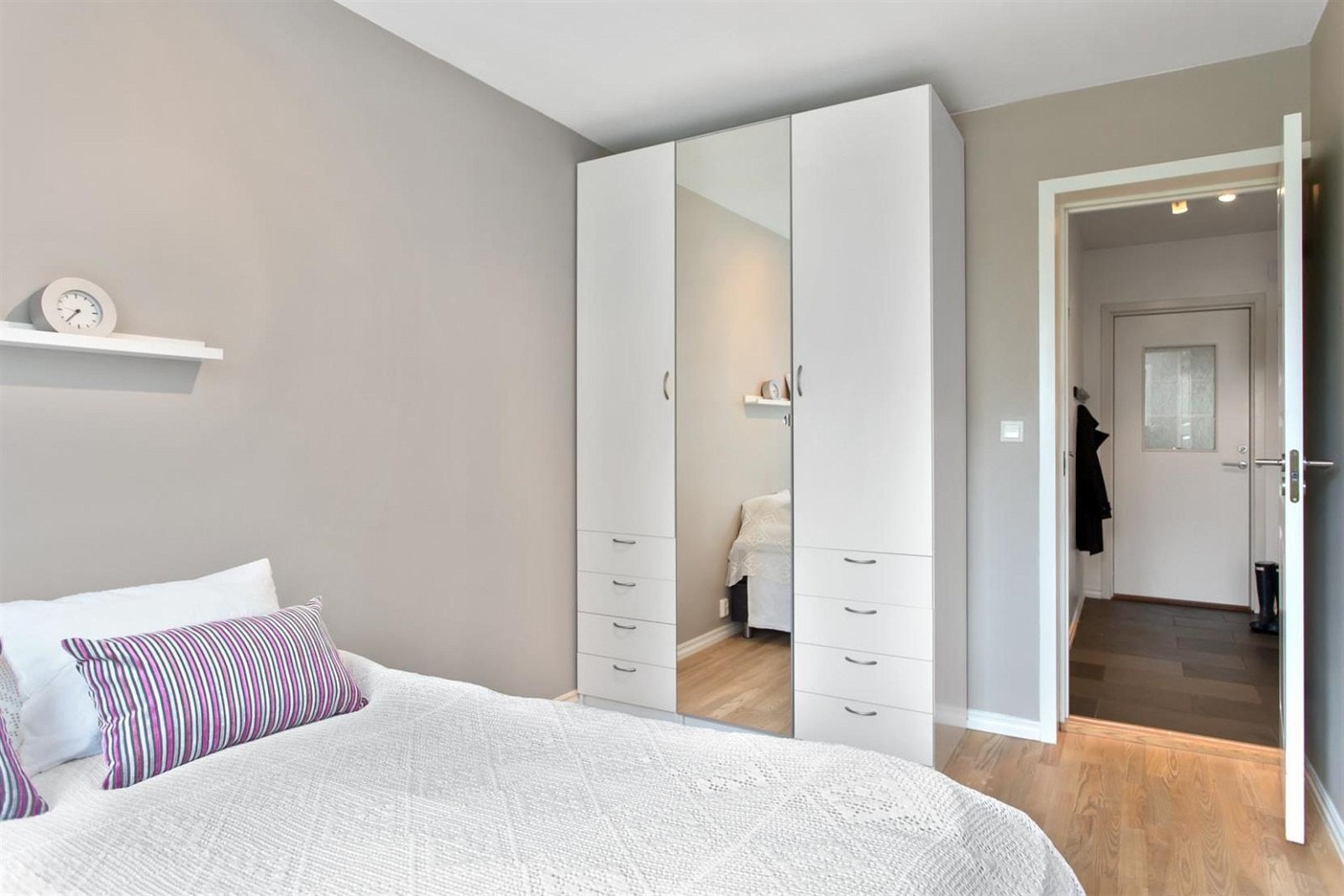 Lyst og behagelig soverom med tilhørende garderobeskap med speil Galleribilde