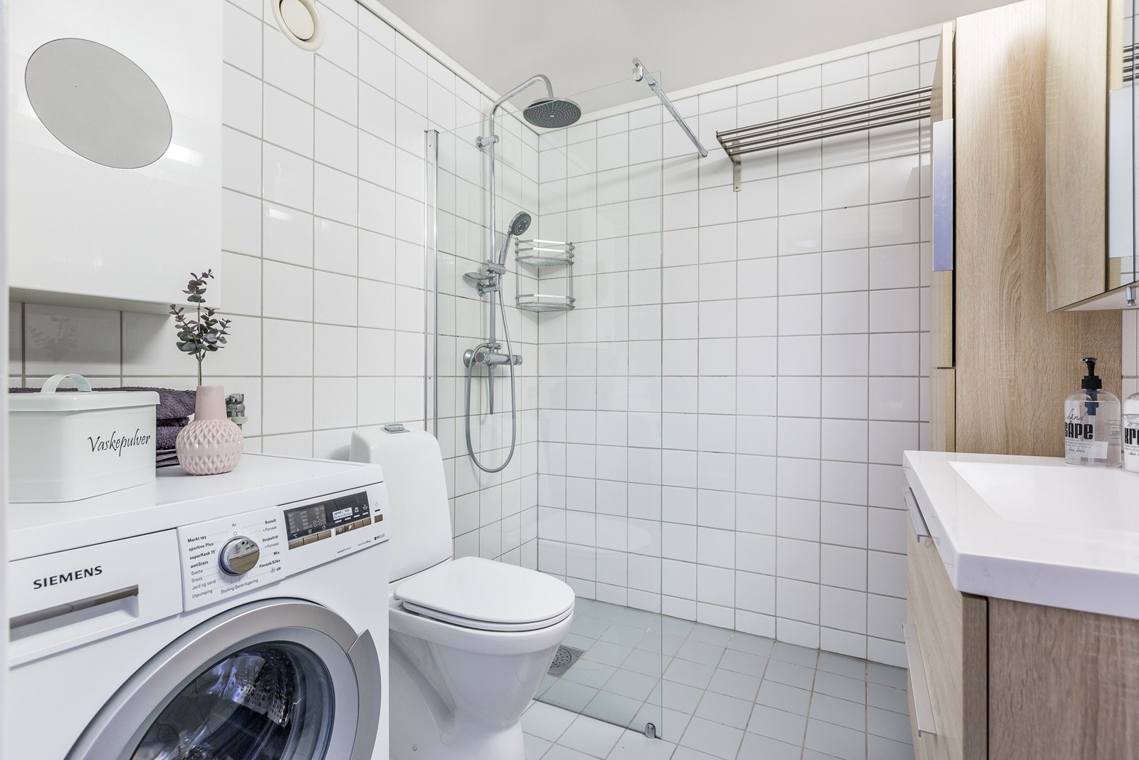 Romslig bad med lyse fliser, varmekabler i gulv og fossefallsdusj i dusjnisje. Galleribilde