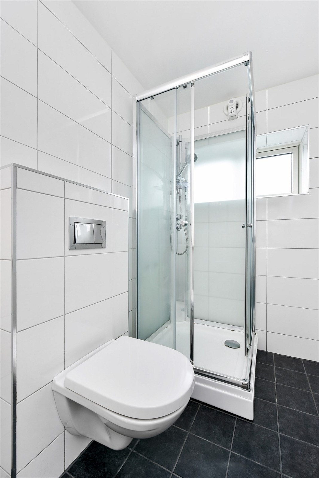 Rommet fremstår som svært pent med fliser på gulv og vegger, gulvvarme og et vindu med godt lysinnfall. Galleribilde