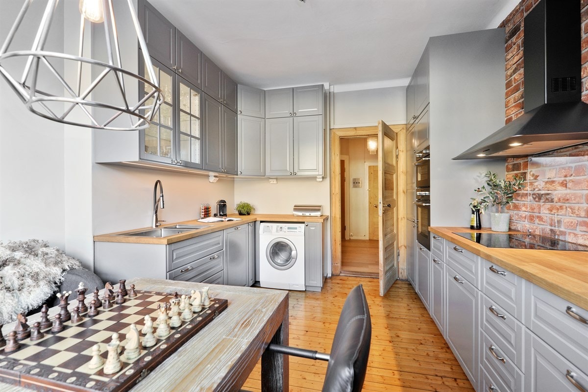 Opplegg for vaskemaskin. Benkeplate med oppvaskkum med flott ettgreps blandebatteri. Sjarmerende teglsteinsvegg på langvegg. Galleribilde