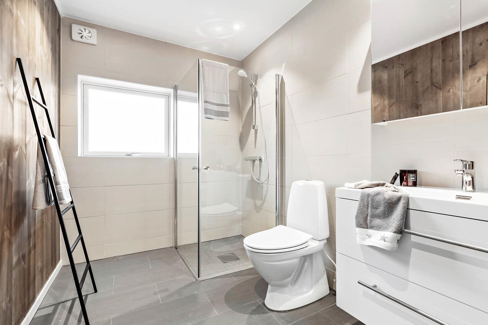 Lekkert bad med store fliser på gulv og i våtsonen. Galleribilde