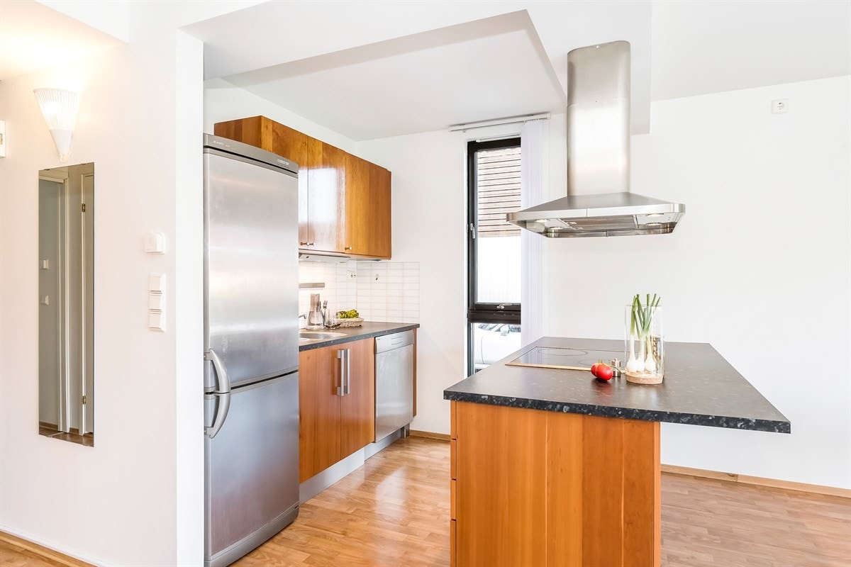 Frontene er i kirsebær med mørk laminert benkeplate, våtromspanel over kjøkkenbenk og integrert komfyr. Galleribilde