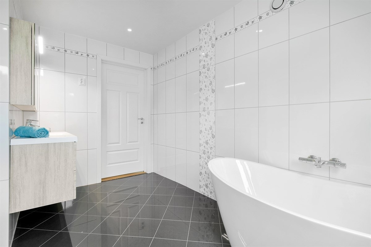 I tillegg har badet et stort og flott servantmøblement med glatte skuffefronter, heldekkende servant og speilskap med lys i overkant. Galleribilde