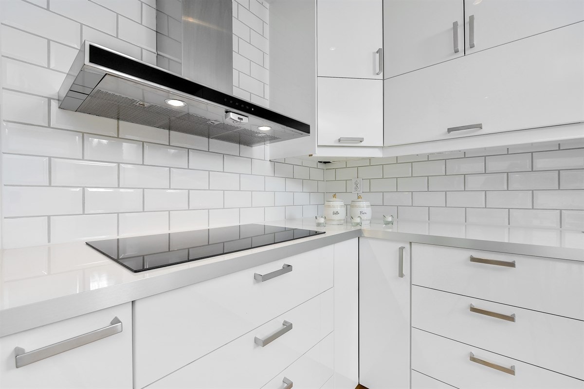 Over benken er det pene, hvite fliser og belysning, samt en fritthengende ventilator over kokesonen. Kjøkkenet har integrerte hvitevarer i form av stekeovn, induksjonstopp og mikrobølgeovn, kjøleskap, fryseskap og oppvaskmaskin. Galleribilde