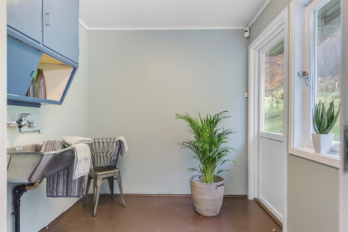 I praktisk tilknytning til kjøkkenet og med egen inngang utenfra ligger vaskerommet fint til i huset. Her kan man lett få satt på en maskin med klær samtidig som man forbereder middagen. Vinduet slipper inn dagslys og har utsikt mot husets bakside. Galleribilde
