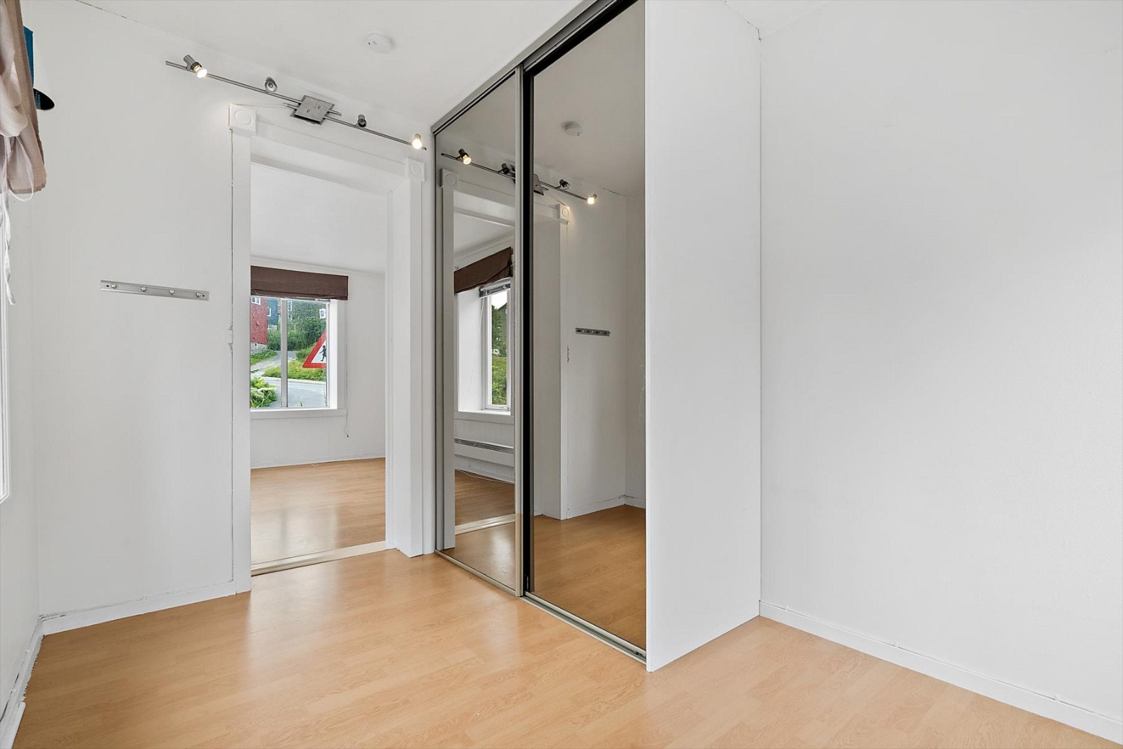 Hvitmalt soverom med skyvedørsgarderobe med speildører. Galleribilde