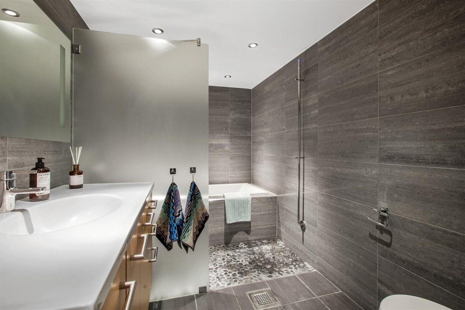 Lekkert flislagt bad med stor heldekkende servant. Det er både dusj og badekar bak glassvegg. Galleribilde