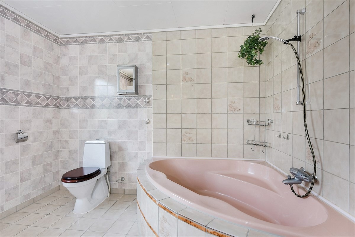Badet har frittstående toalett og innfliset hjørnebadekar. Galleribilde