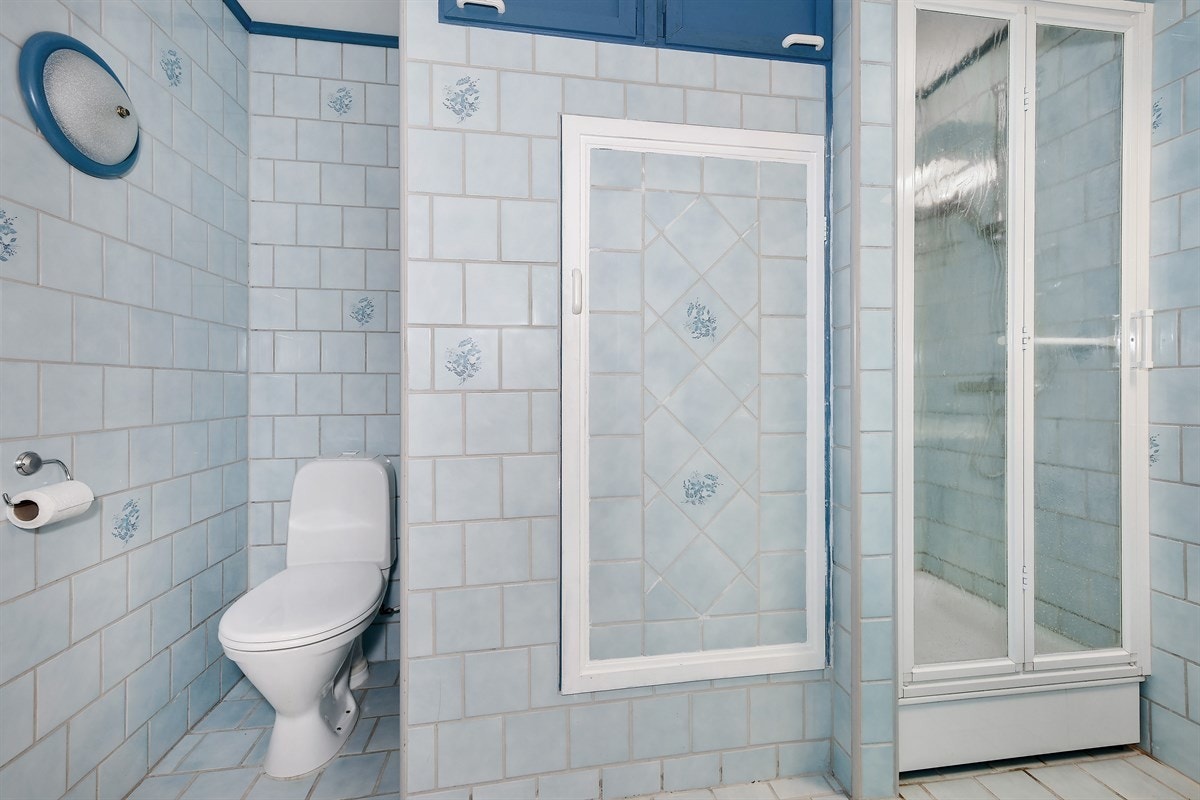 Det flislagte badet i underetasjen har gulvvarme, frittstående toalett og dusjhjørne med skyvedører og dusjkar. Galleribilde